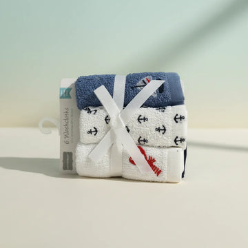 Nautical baby washcloths 6 pack bundled with white ribbon bow on retail hanger card showing navy blue terry top with sailboat motif white anchor print washcloths and red lobster embroidery cloth on soft teal cream studio background