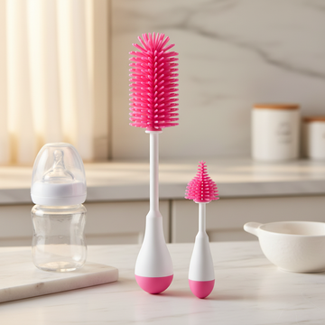 Pink silicone baby bottle brush set – kitchen lifestyle scene on marble counter with baby bottle, showing large and small brush upright
