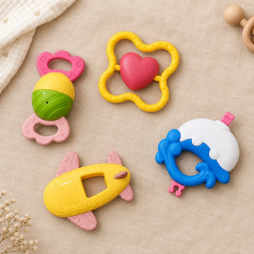 Pink, green, yellow, and blue baby rattles displayed on a beige surface