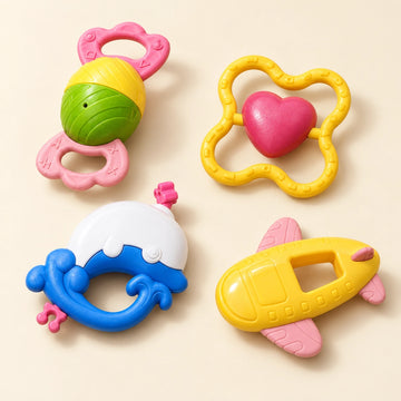Four bright baby rattle toys arranged in a softly lit setting