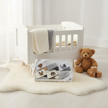Baby Woodland Animal Socks 5 Pair Gift Box - cozy nursery scene on white fur rug with white crib and teddy bear