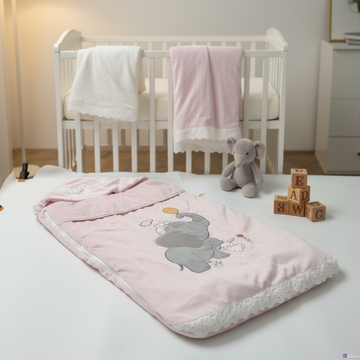 Pink elephant bunny baby sleeping bag – cozy nursery scene open on white bed next to white crib and elephant plush toy