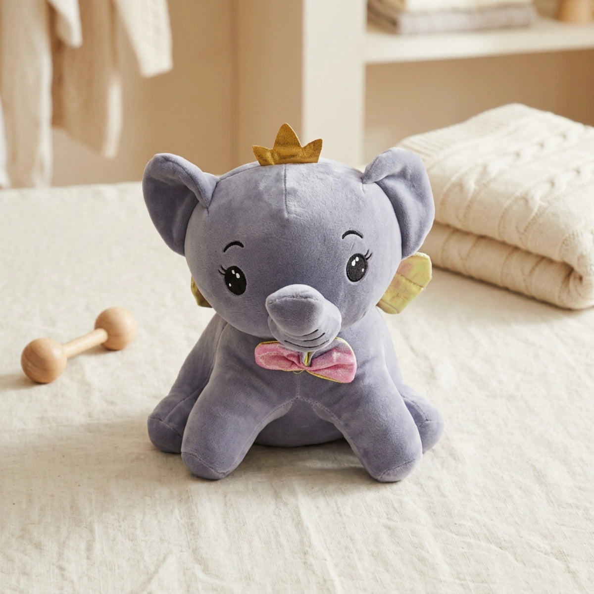 Grey elephant plush with golden crown and wings in a warm lifestyle setting