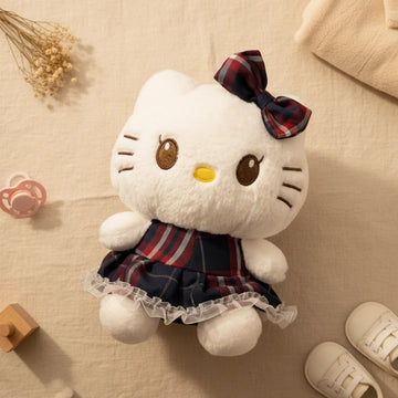 Hello Kitty tartan plaid dress plush toy flat lay from above on linen background showing white Hello Kitty plush in navy red tartan dress with white lace frill hem matching tartan bow gold winking left eye brown right eye and yellow nose beside dusty pink pacifier wooden toy white baby sneakers and dried grass stems