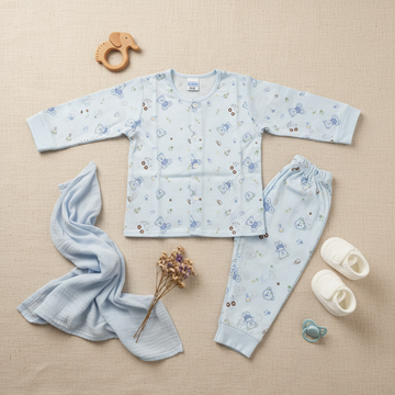 Mamo Blue Bear Bunny Print Baby Pyjama Set - lifestyle flat lay on beige linen with wooden elephant teether white baby booties teal pacifier dried lavender flowers and light blue muslin cloth