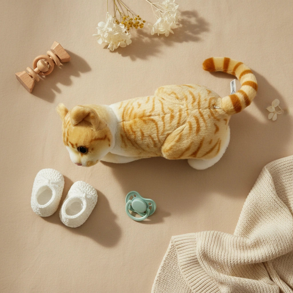 Tabby the Kitten plush toy flat lay with baby essentials on beige background