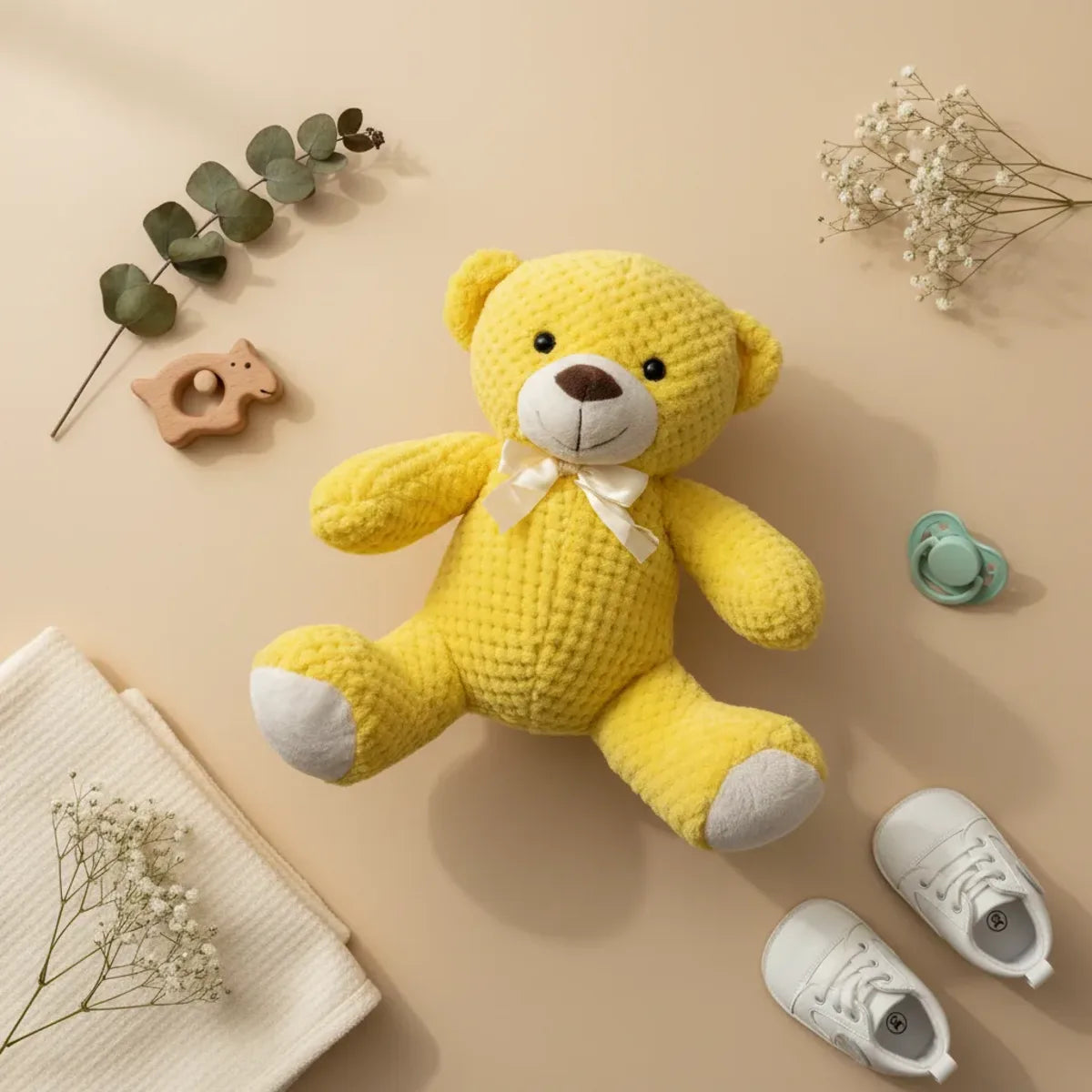 Sunny the Yellow Waffle Teddy Bear flat lay with baby shoes pacifier and eucalyptus sprigs