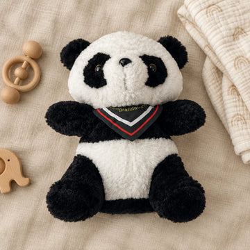Panda plush toy on a neutral beige blanket beside wooden baby toys