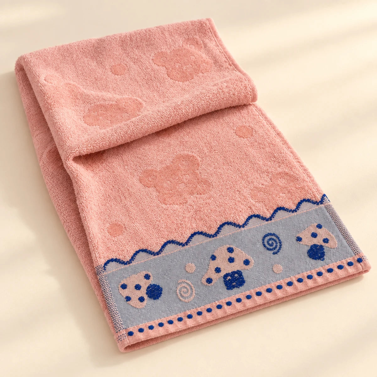 Pink baby towel with duck border draped over a soft surface