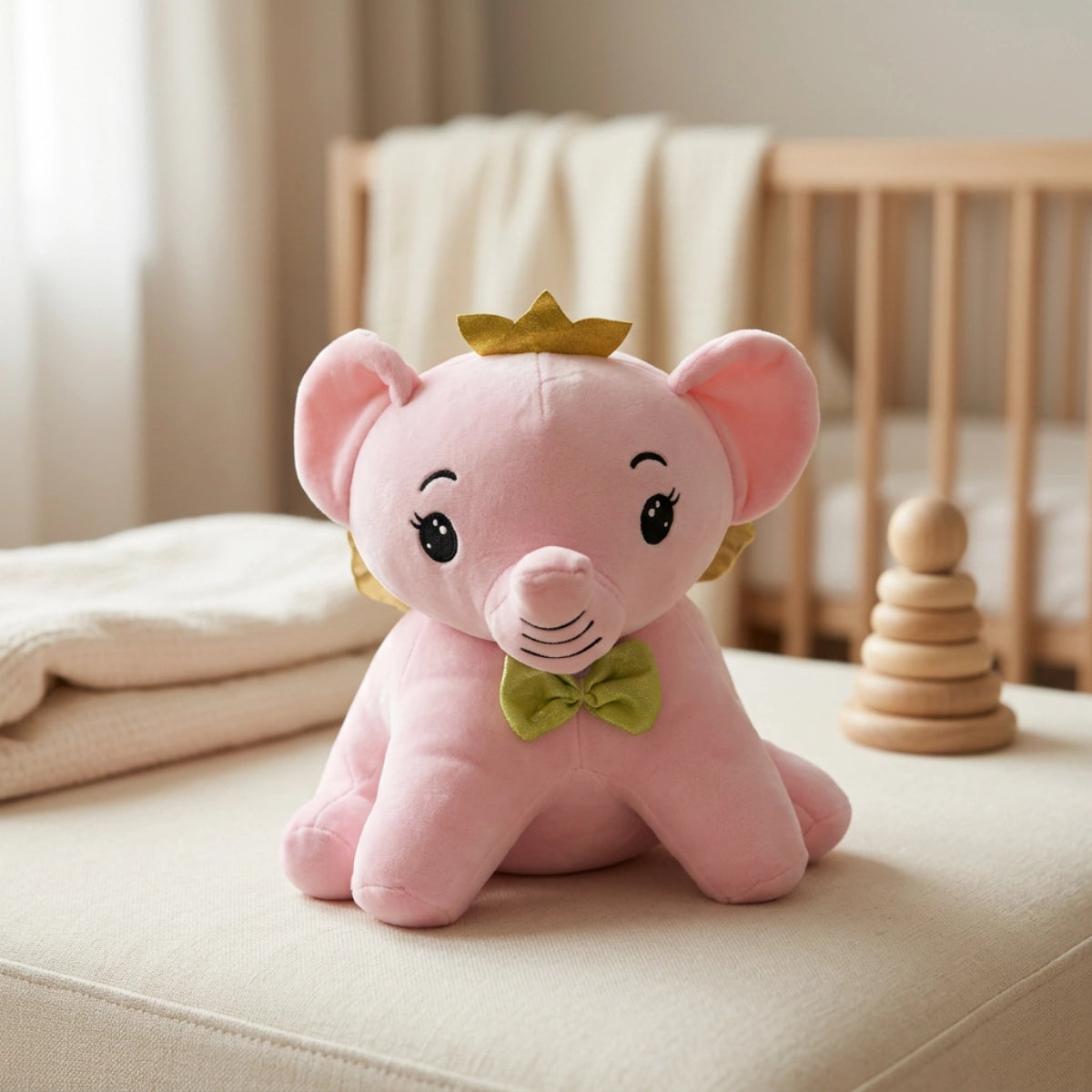 Pink crowned elephant plush with gold wings and green bow tie in a nursery