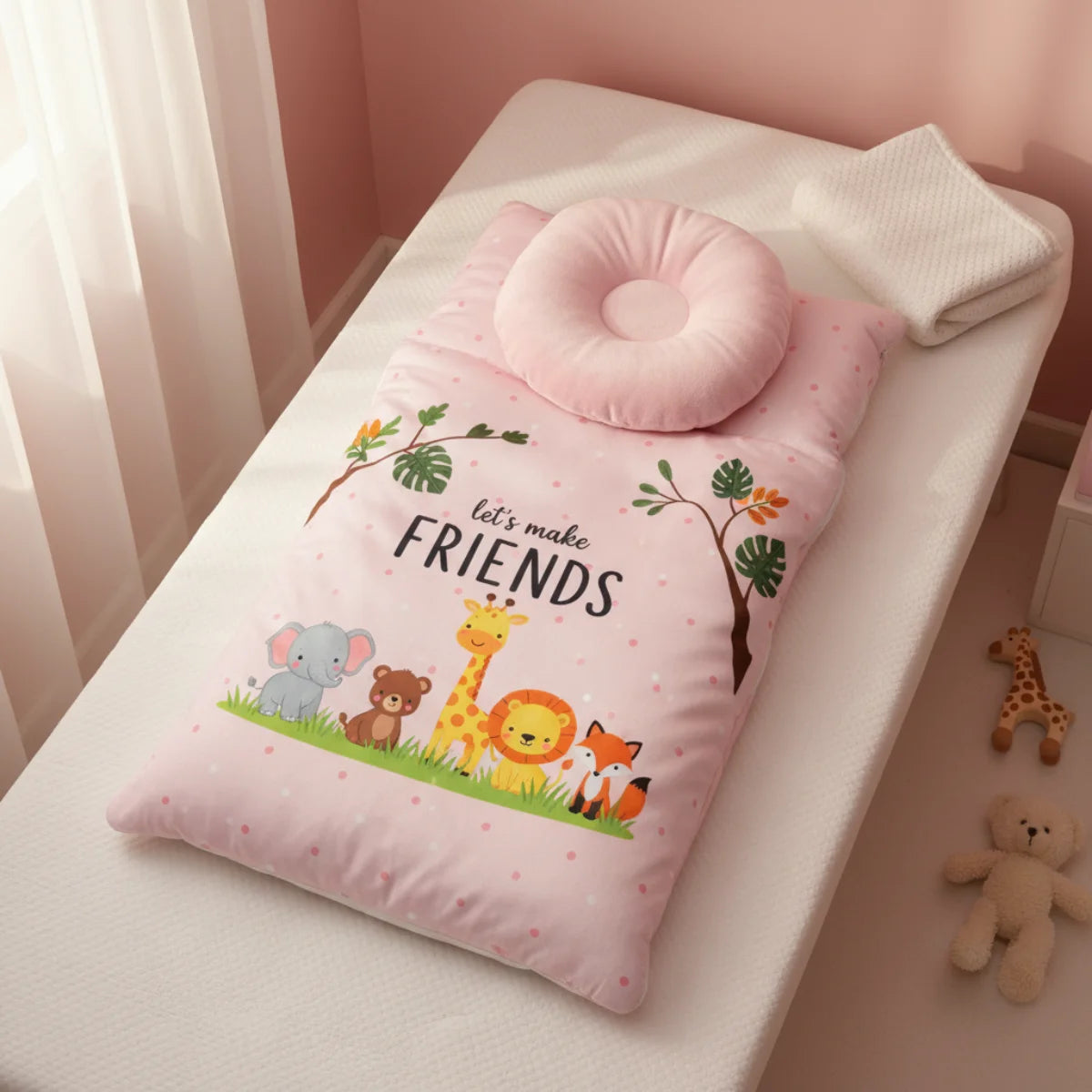Pink baby sleeping bag nursery scene laid flat on white cot mattress in pink nursery room with sheer curtains showing let's make friends safari print with elephant bear giraffe lion fox and pink donut pillow with white star sherpa blanket folded beside and small giraffe and bear soft toys on floor