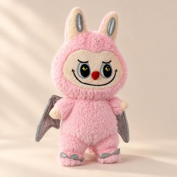 Pink plush character with silver-gray wings in a softly lit scene