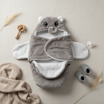 Grey elephant hooded swaddle wrap – lifestyle flat lay with grey booties, wooden rattle, pacifier and pampas grass