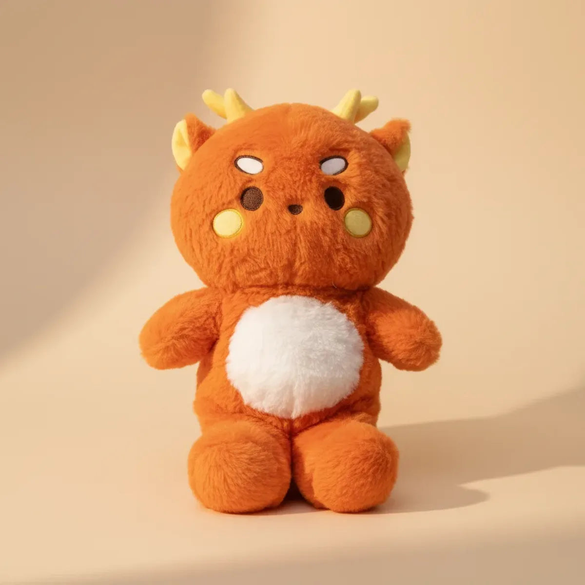 Ember the Orange Dragon plush toy – studio shot on warm beige background