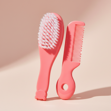 Pink baby hair brush and comb set – premium studio scene on peach background showing both pieces upright with soft bristles detail