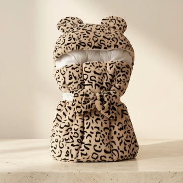 Leopard Bear-Ear Baby Nest showing plush faux fur leopard print pod with 3D bear ears hood and matching bow pillow in studio on cream background